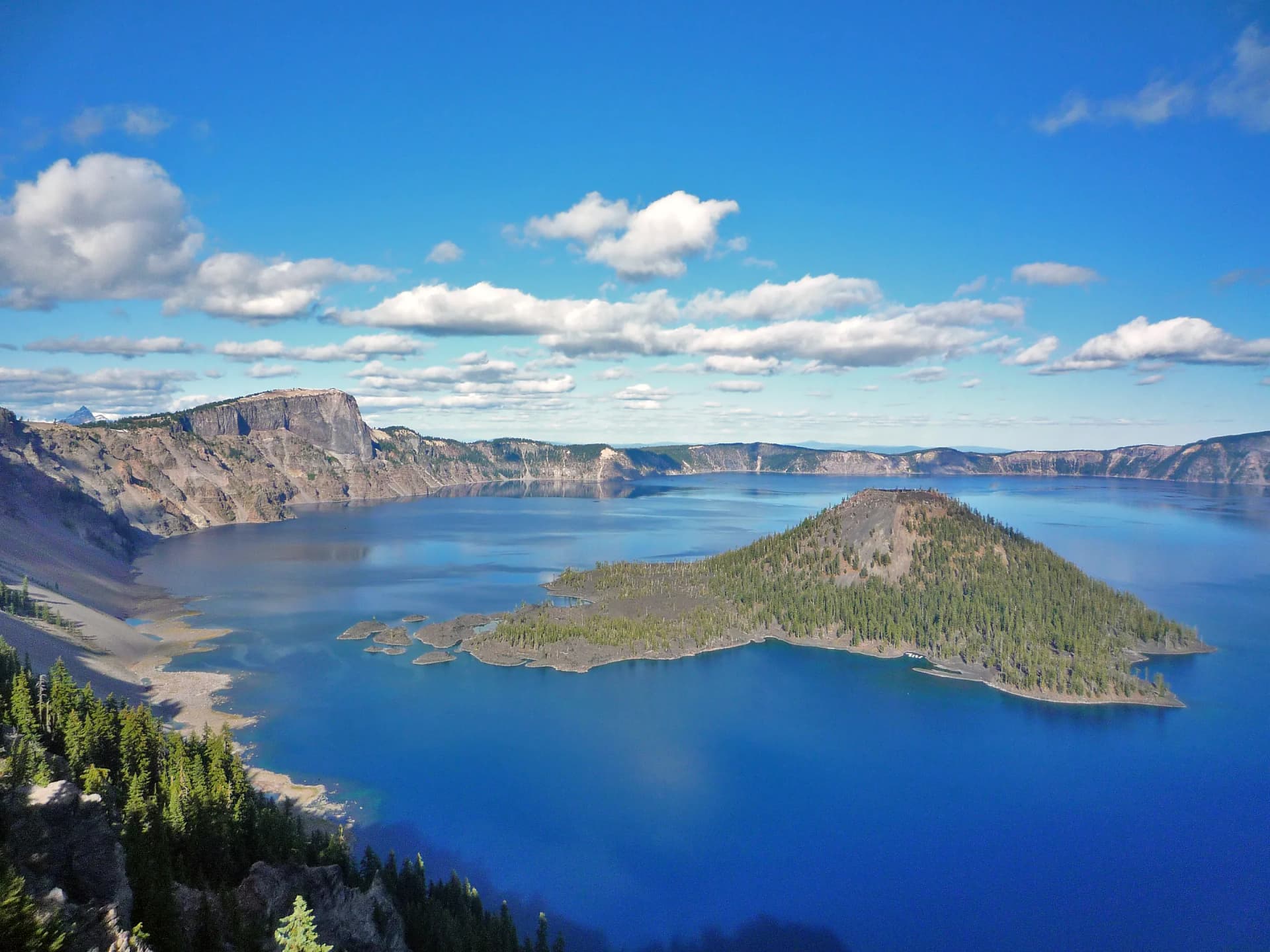 Crater Lake's deep blue water and Wizard Island under summer clouds, seen from the West Rim
