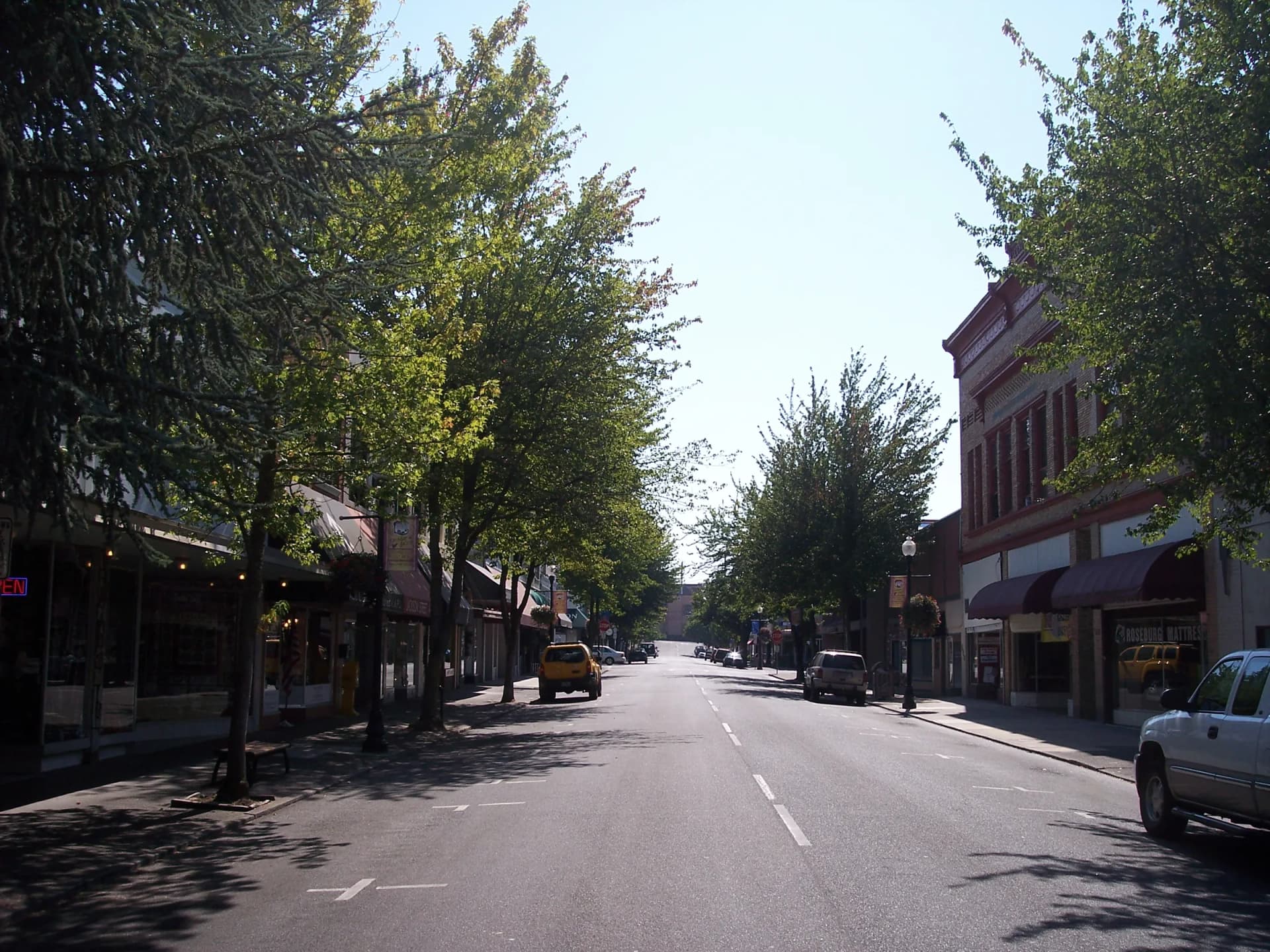 A tree-lined street of historic brick storefronts in downtown Roseburg