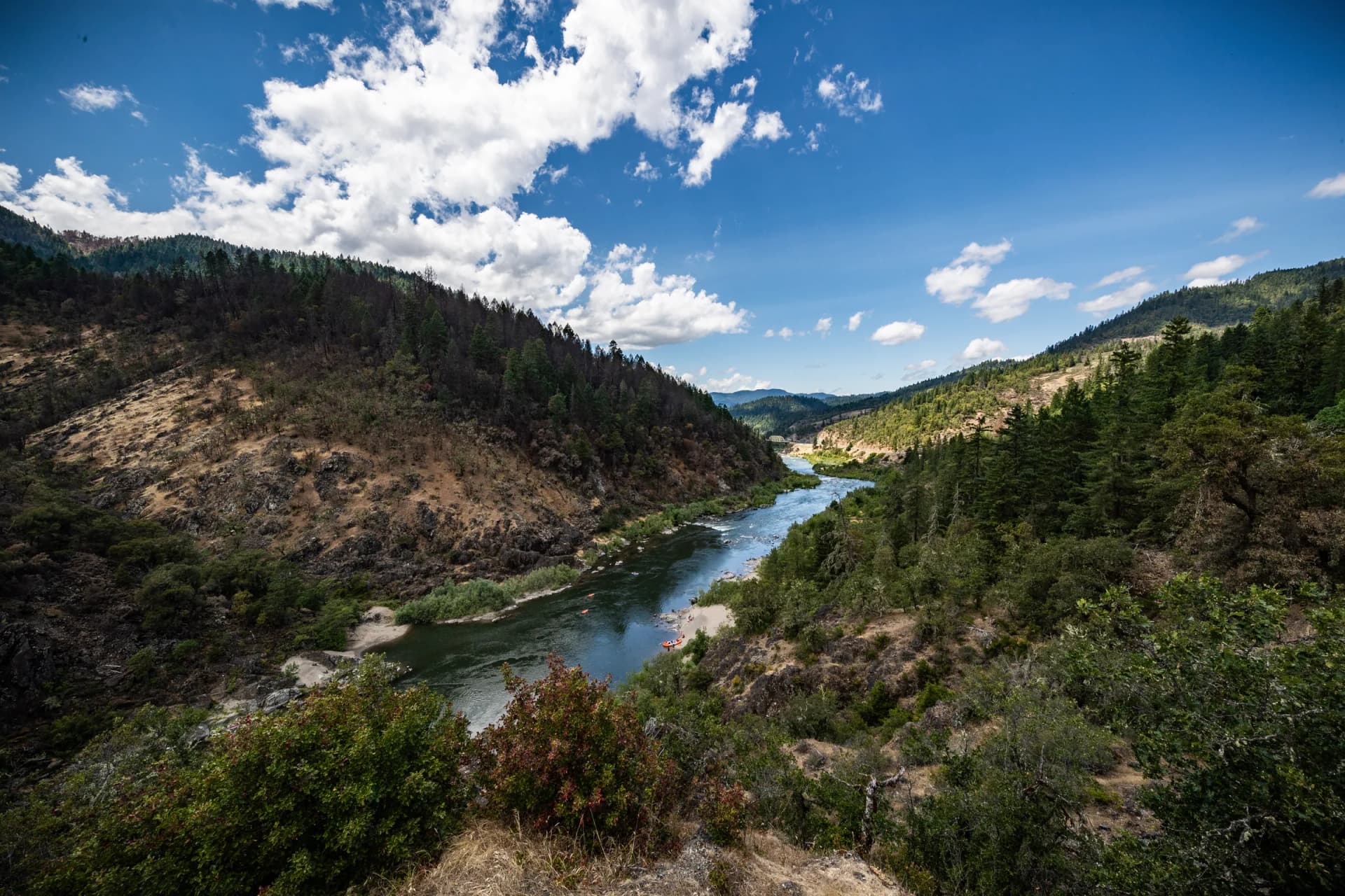 The Rogue River winding through Hellgate Canyon under summer clouds